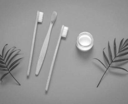 top view bamboo eco friendly tooth brushes, tooth paste jar and green tropical leaves, homemade toothpaste and dental care concept